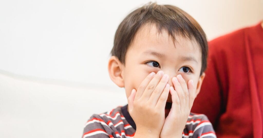 child with hands over his mouth, concept of child's bad breath