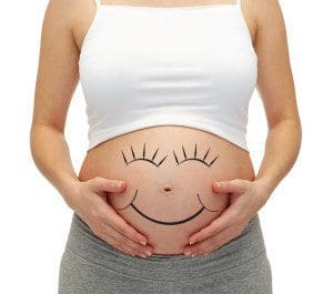 close up of pregnant woman touching her bare tummy