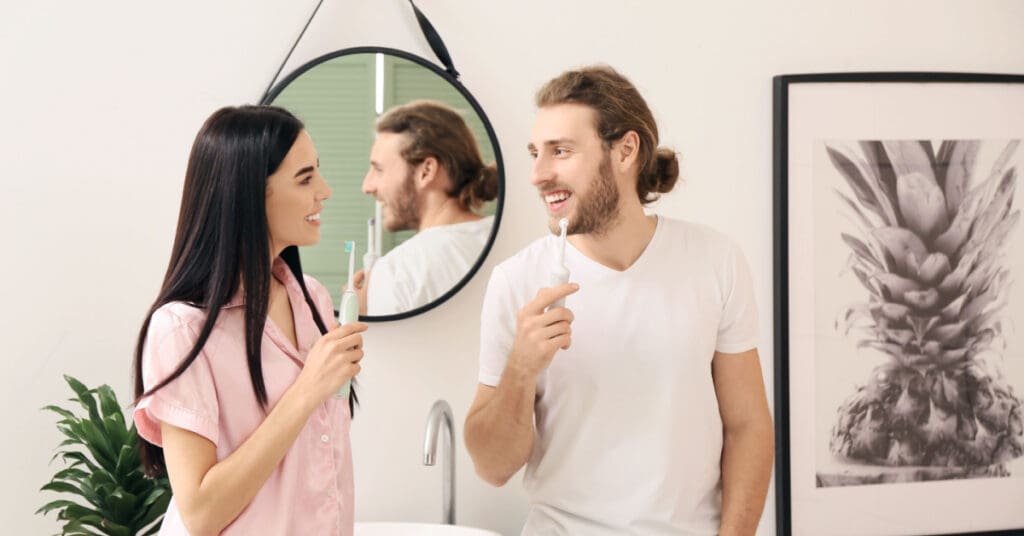 man and woman holding toothbrushes looking at each other