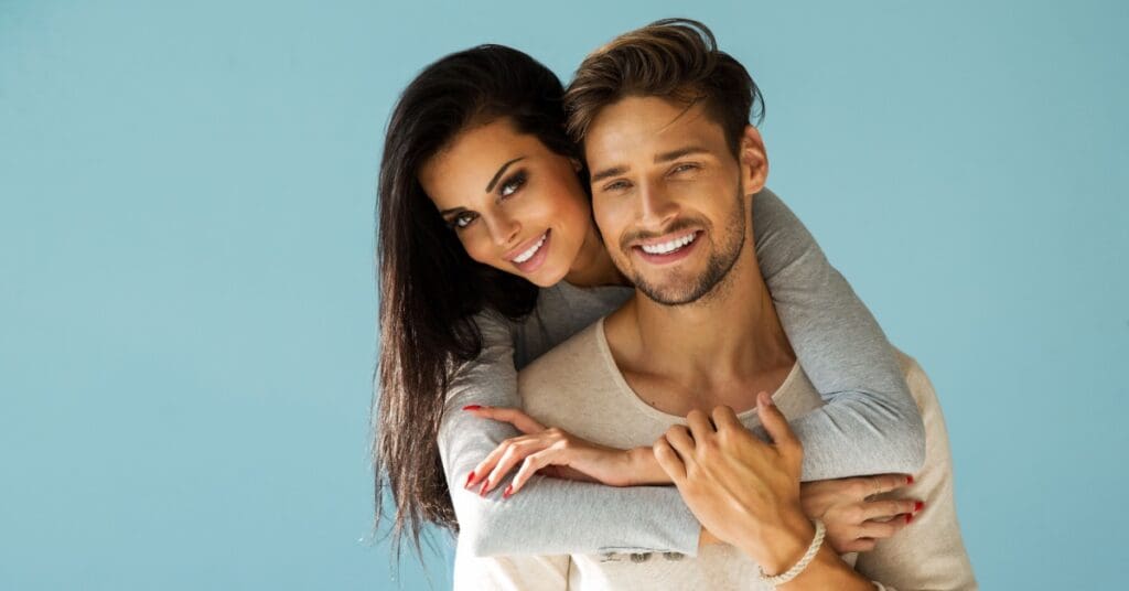 girl with arms around man and both smiling