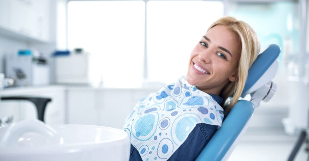 girl in dentist chair with bib smiling