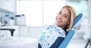 girl in dentist chair with bib smiling