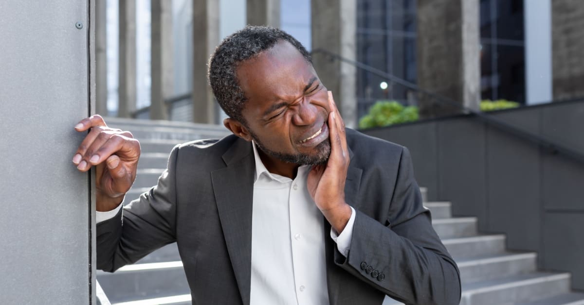 man holding his mouth in pain