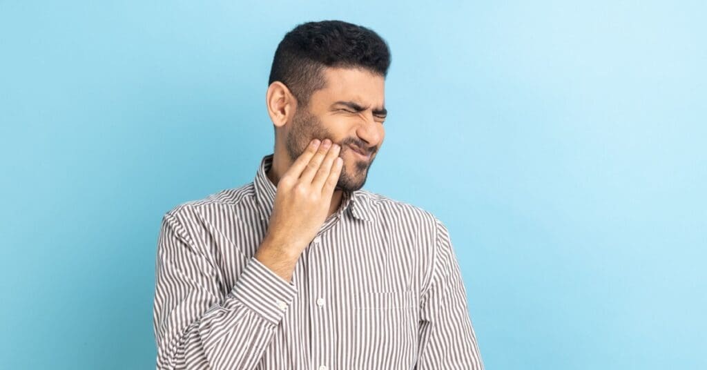 man holding cheek in pain, concept of sudden tooth sensitivity to cold